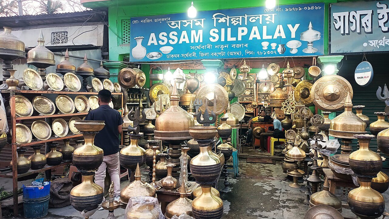 Shelves of brass and bell-metal pots, plates and lamps in a utensil shop at Sarthebari, Assam